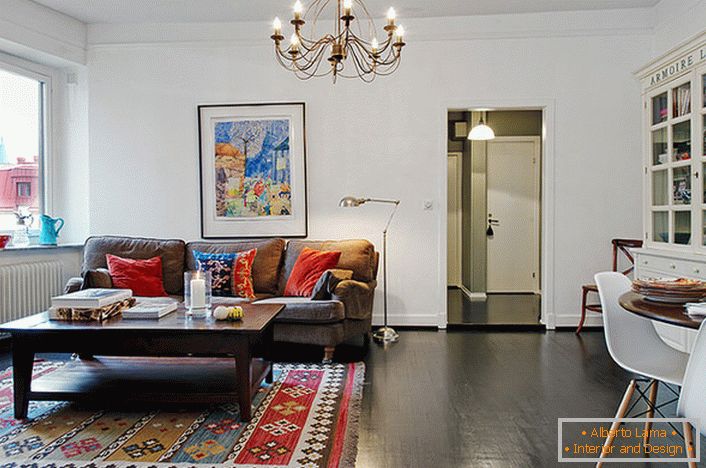Елегантна соба за госте у типичном апартманском апартману уређена је сјајним јастуцима на софи и тепиху. 