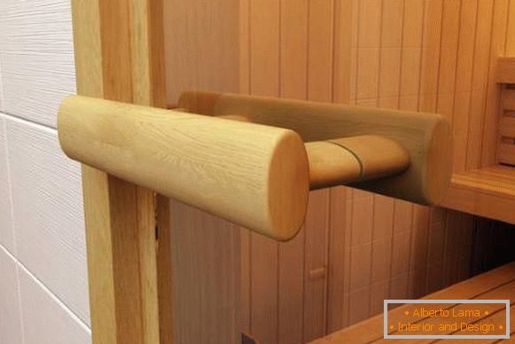 Дрвена ручка за стаклена врата у сауни направљеној од кречњака