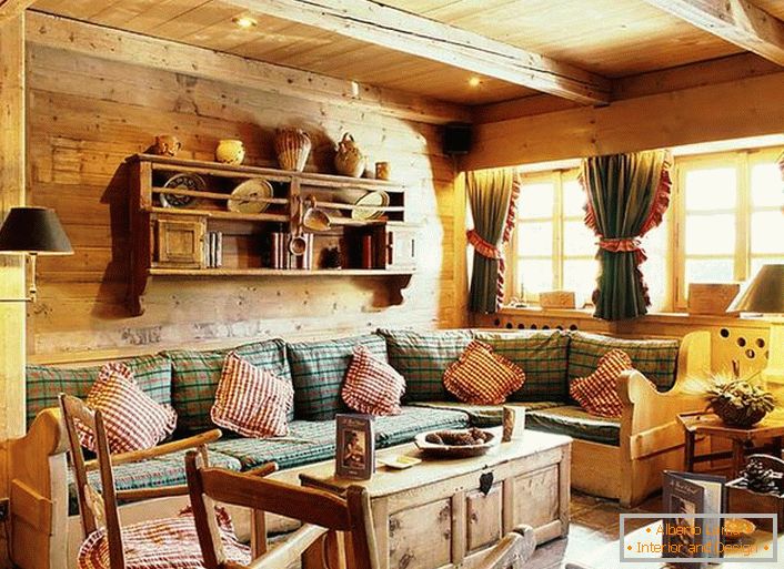 Дрвена зидна декорација, контрастни јастуци на меканом софу, густе завесе са рупу на прозорима. Удобан дневни боравак у рустикалном стилу у сеоској кући.