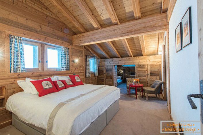Пространа спаваћа соба на другом спрату куће из дрвене брвнара. В соответствии со стилем кантри искусственный свет в комнате приглушен. 