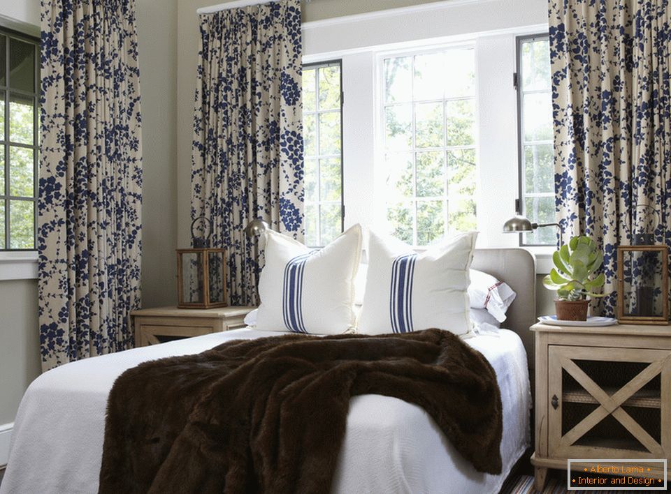 Плаво цвијеће на завјесама и пругама на јастуцима хармонично се комбинује у унутрашњости спаваће собе