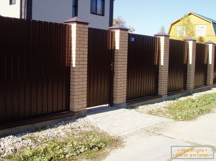 Модуларна ограда је тамно браон с завршном облогом од цигле - класика жанра, ако се ради о дизајну приградских подручја.