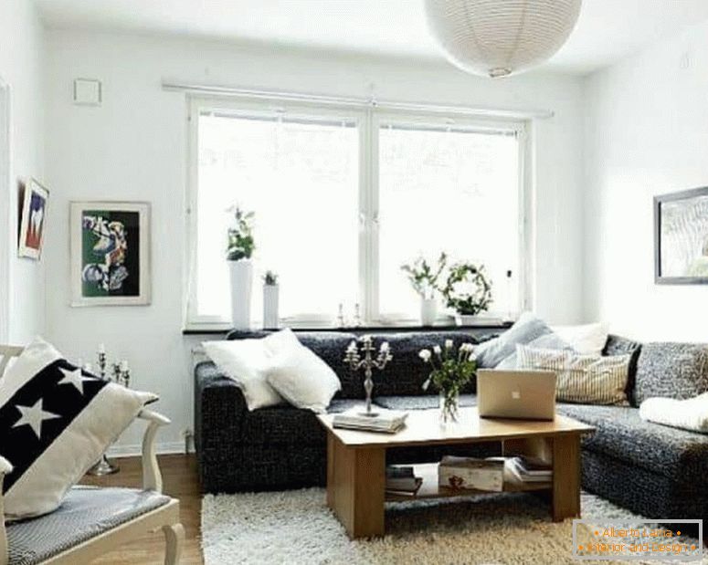 Мала дневна соба у белој боји са тамним угловним софом и прозорима