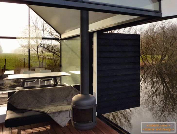 Тераса мале стаклане куће поред језера у Холандији